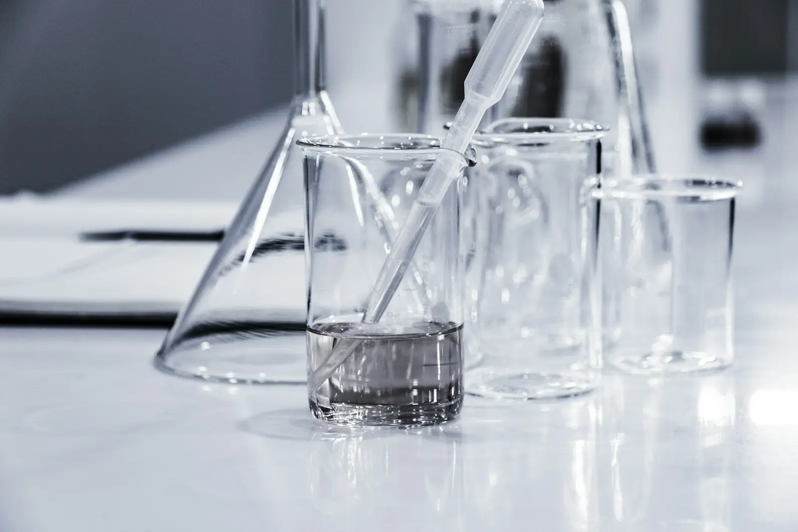 Drei Bechergläser aus Glas auf einer hellen Laborfläche.