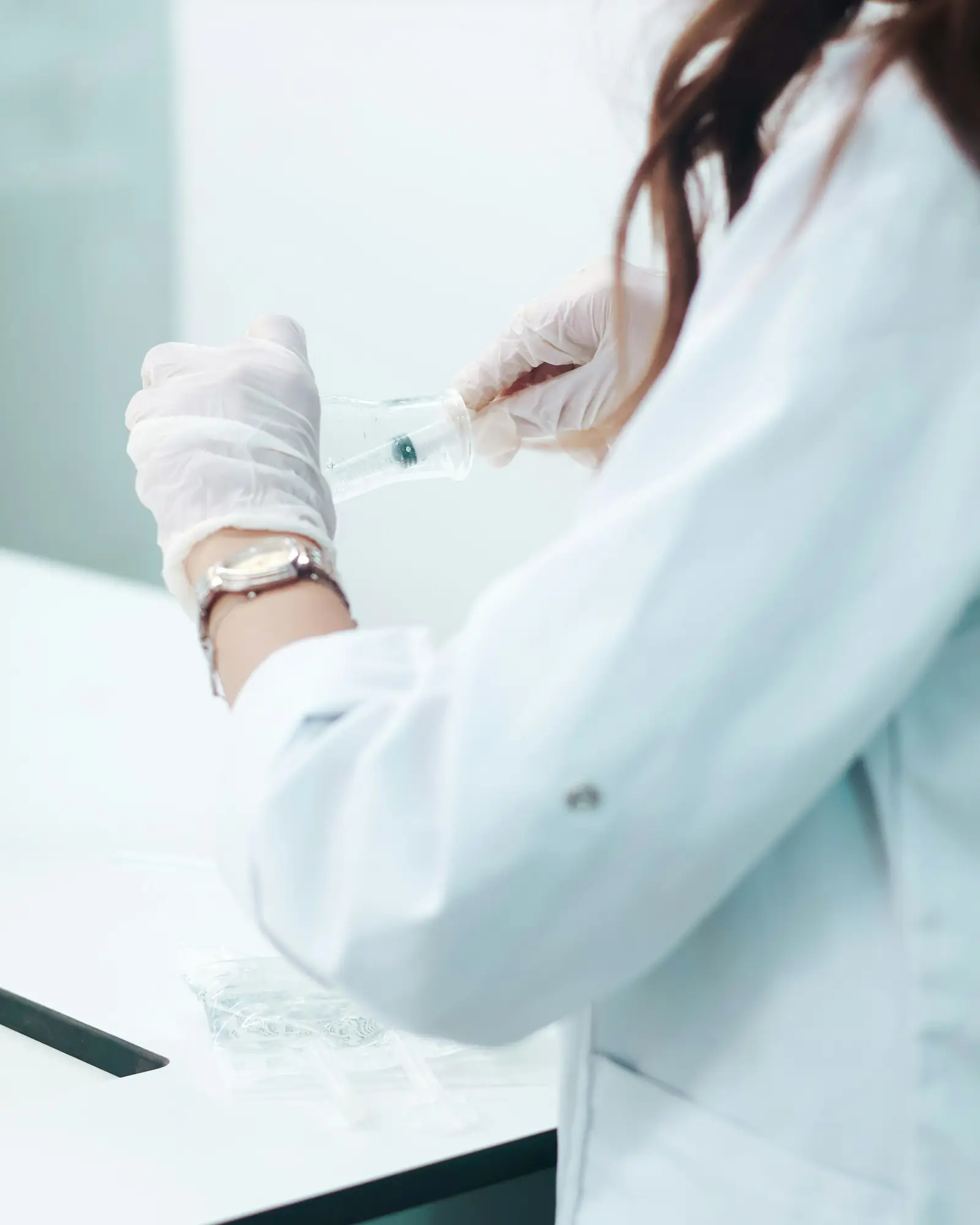 Eine Laborantin mit Schutzhandschuhen arbeitet mit einer Pipette.